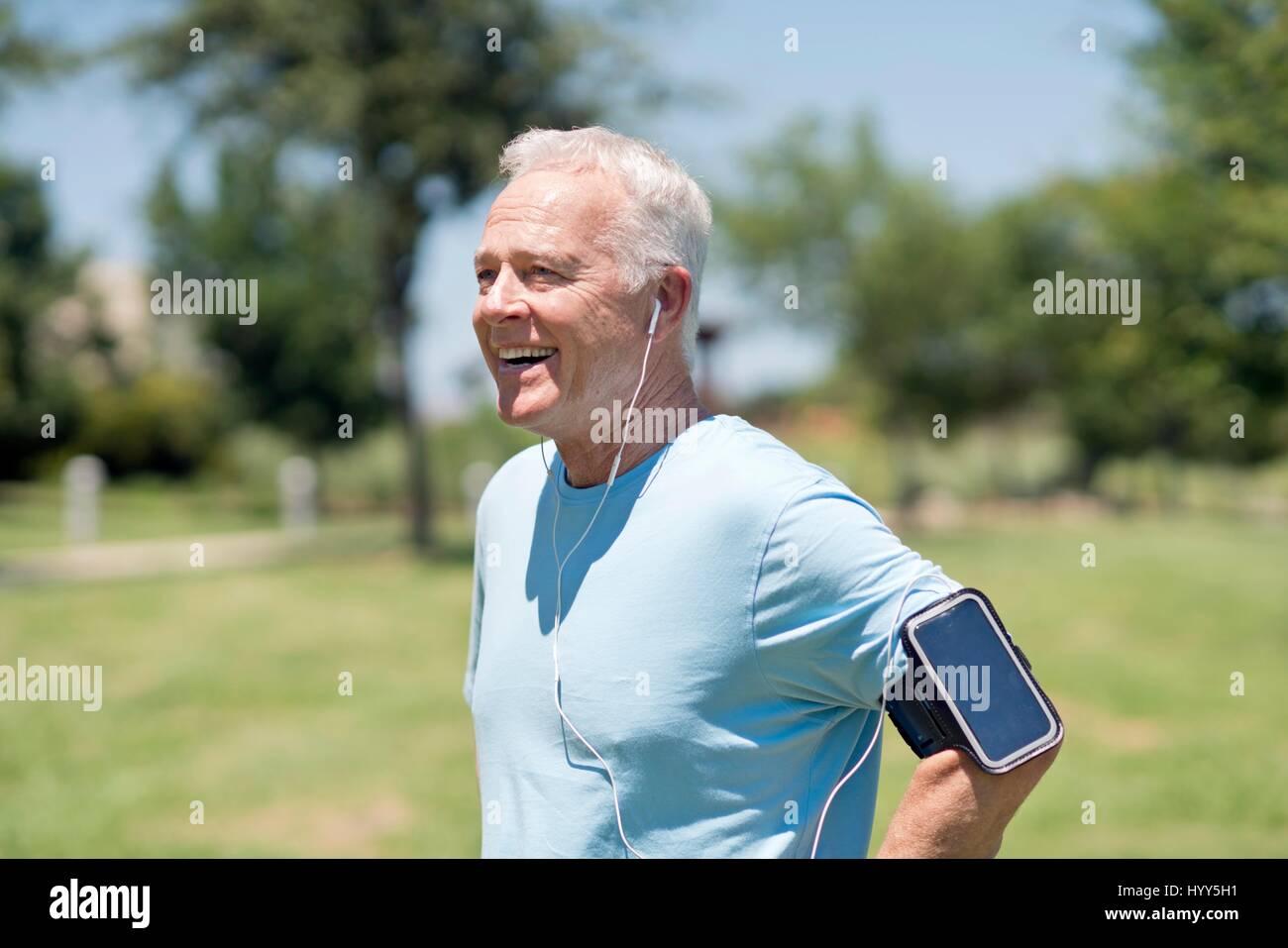 Senior uomo smartphone da indossare sul braccio e auricolari nel parco. Foto Stock