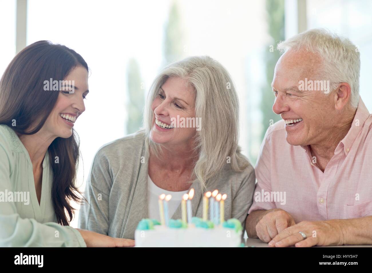 Coppia senior e figlia adulta con torta di compleanno. Foto Stock