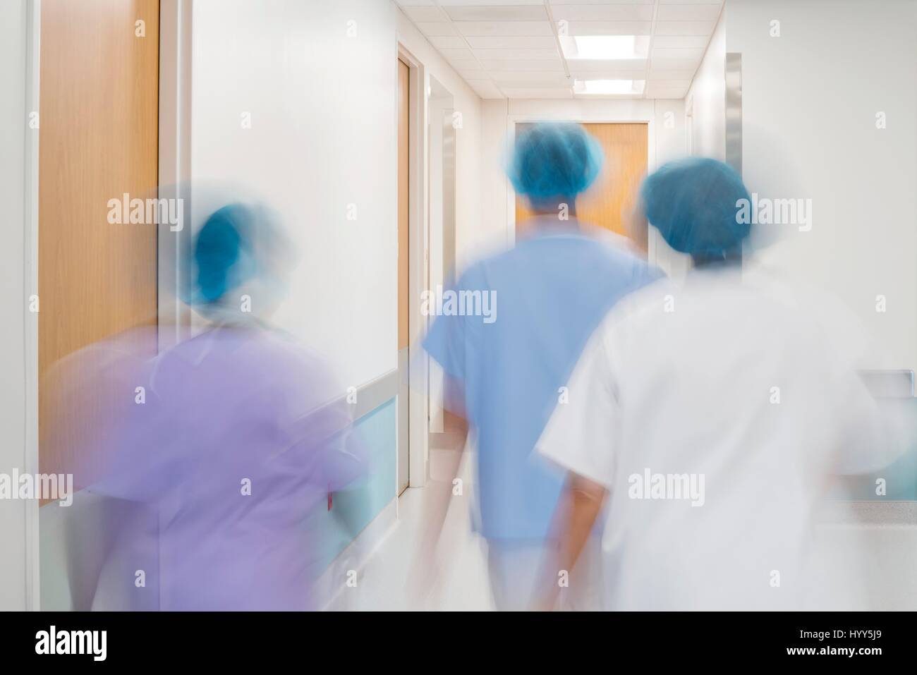 Il personale medico a piedi giù il corridoio dell'ospedale. Foto Stock