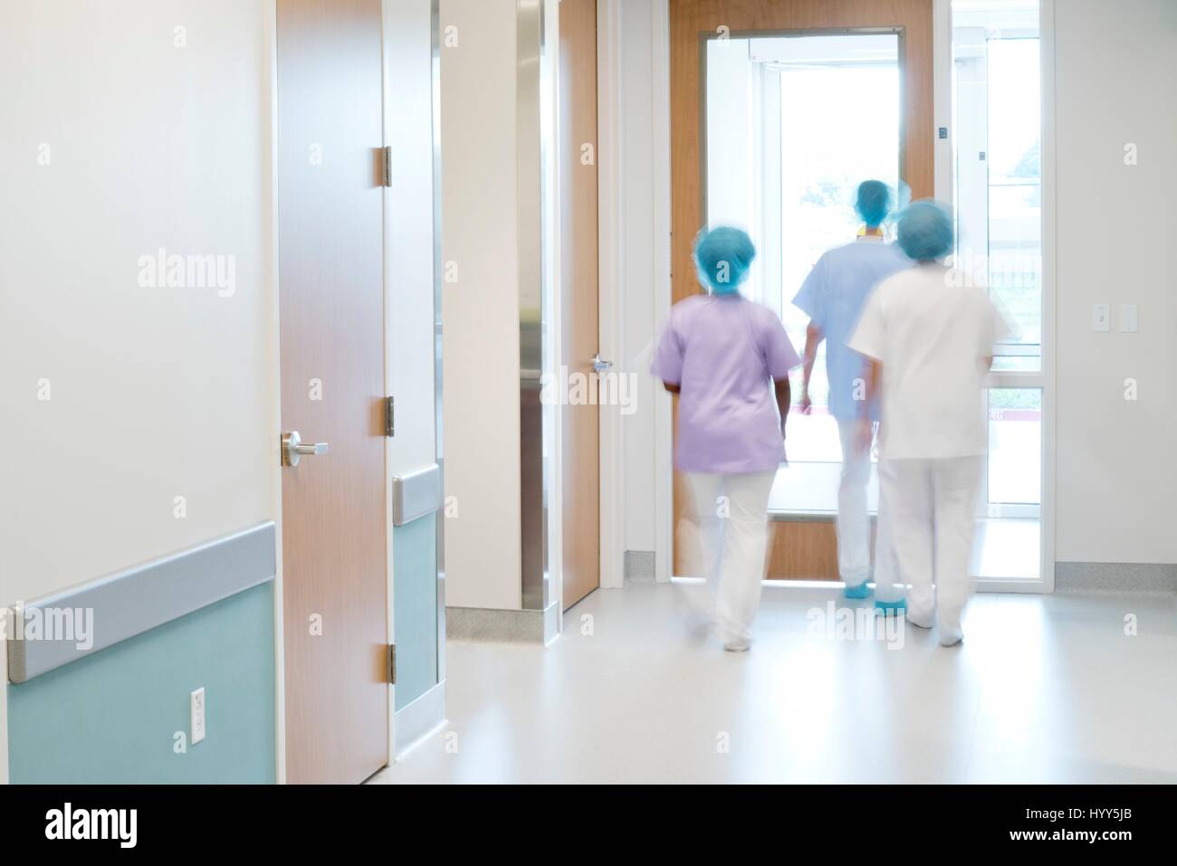 Il personale medico a piedi giù il corridoio dell'ospedale. Foto Stock