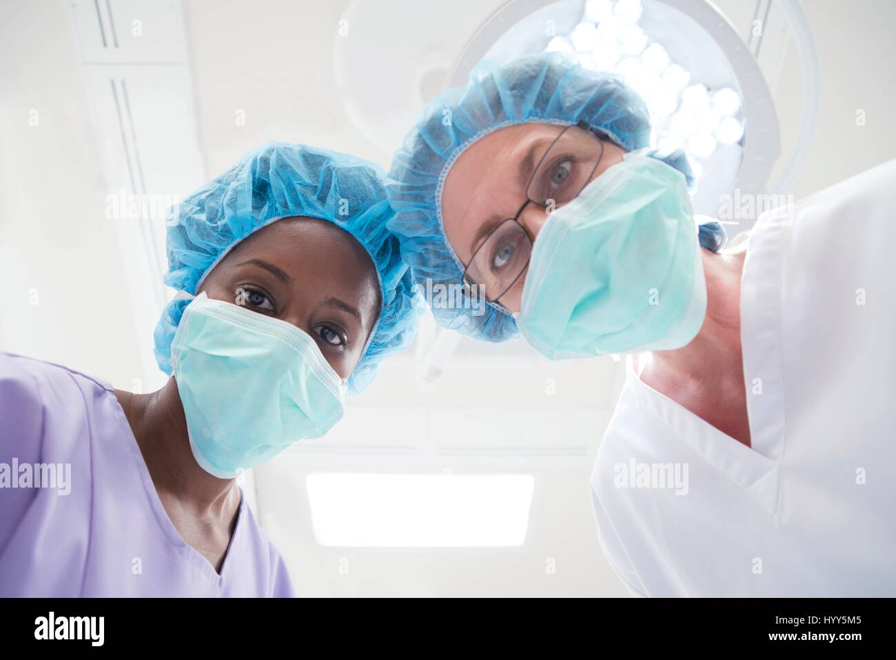 Due chirurghi femmina guardando verso la telecamera, prospettiva personale. Foto Stock