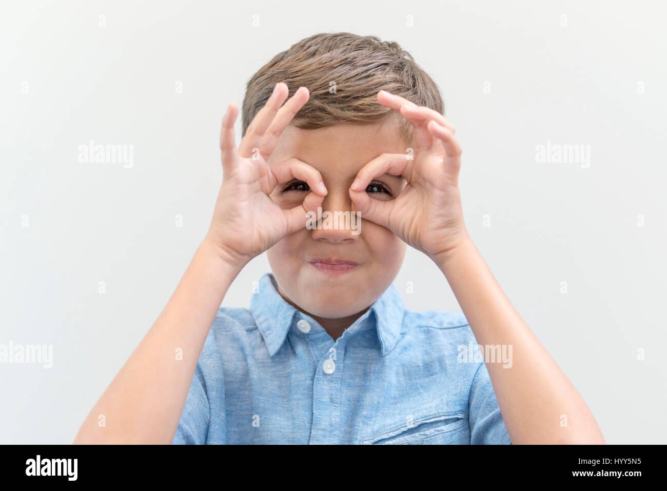 Ragazzo che finge di indossare occhiali guardando attraverso le dita. Foto Stock