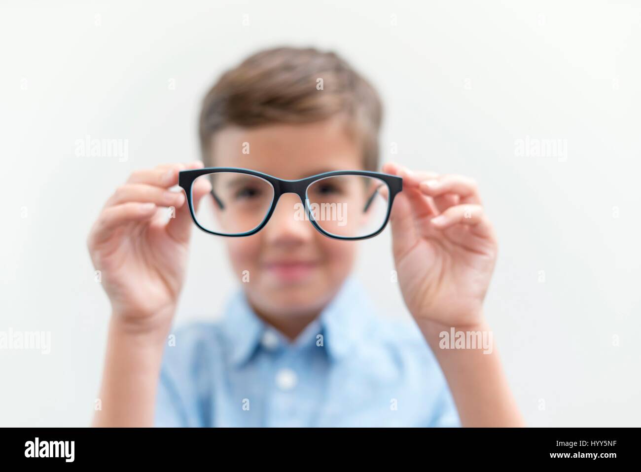 Ragazzo holding bicchieri e guardando attraverso di loro. Foto Stock