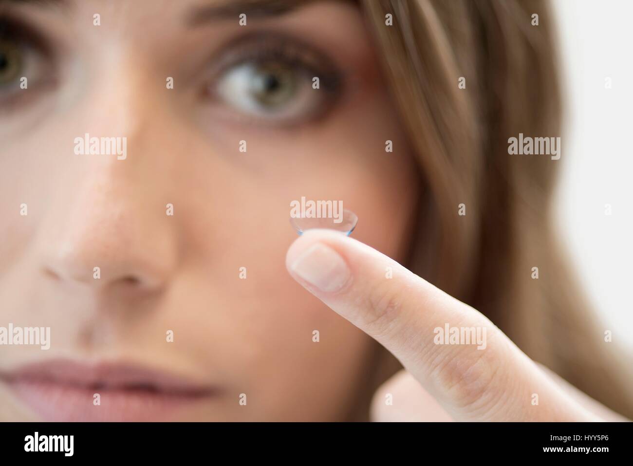 Metà donna adulta con lente di contatto sul dito. Foto Stock