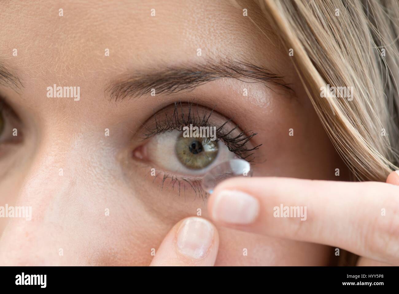 Metà donna adulta mettendo la lente a contatto oculare. Foto Stock
