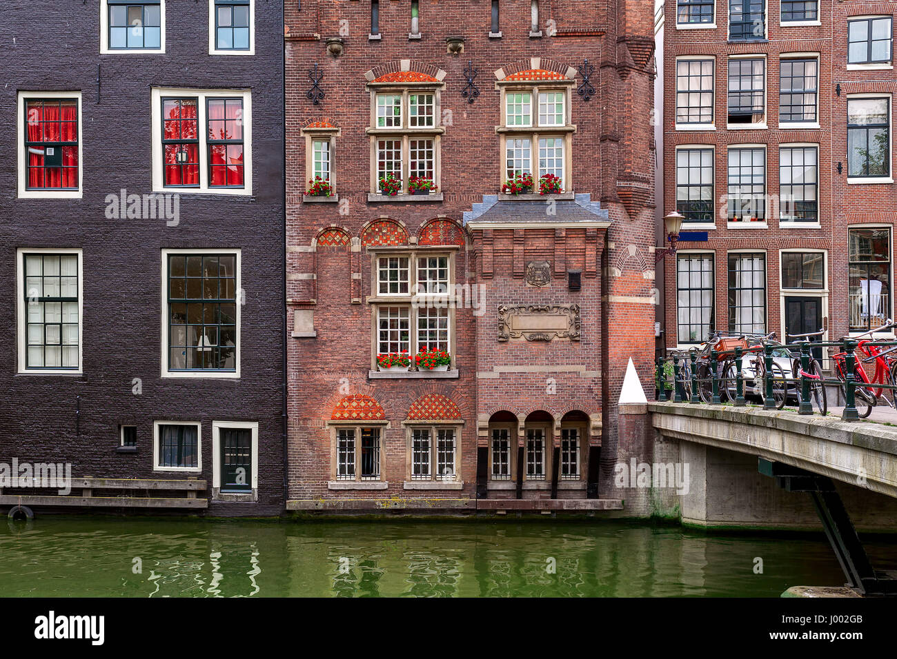 Vista del tipico di età compresa tra i mattoni di edificio residenziale e piccolo ponte con le biciclette in Amsterdam, Paesi Bassi. Foto Stock