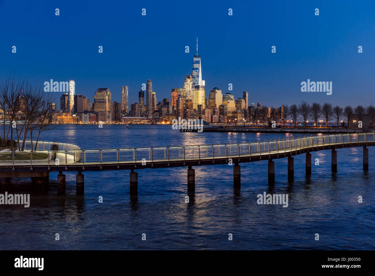New York City Financial District grattacieli al tramonto e sul fiume Hudson da Hoboken promenade. Inferiore dello skyline di Manhattan e il ponte pedonale Foto Stock