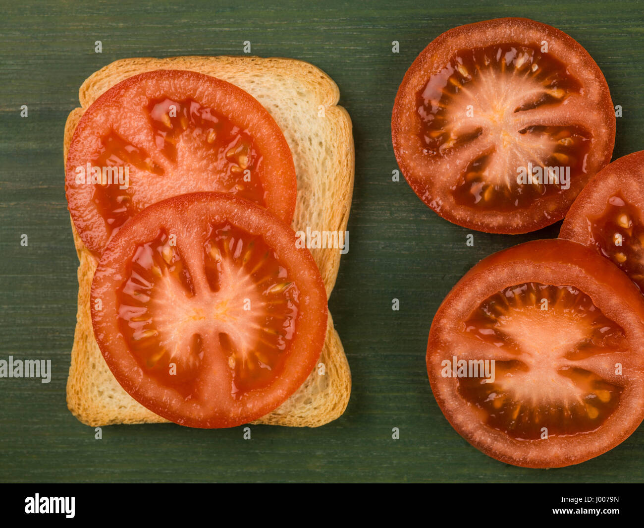 Fette di pomodoro su toast francesi contro uno sfondo verde Foto Stock