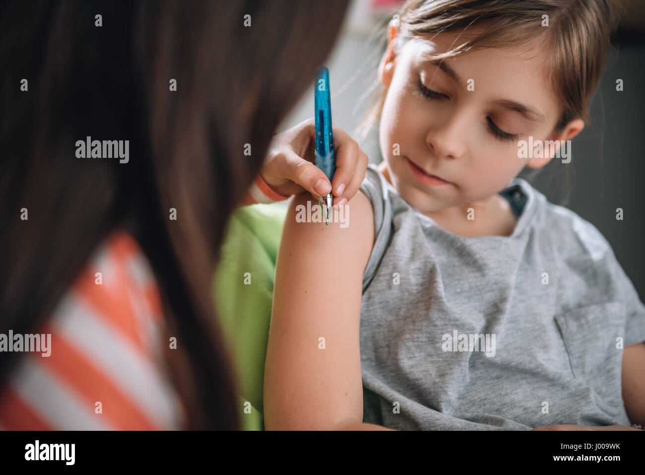 Ragazza iscritto tatuaggio sul braccio della sua fidanzata con penna Foto Stock