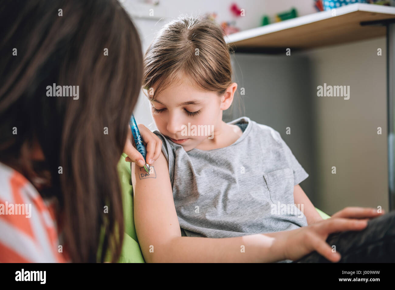 Ragazza iscritto tatuaggio sul braccio della sua fidanzata con penna Foto Stock