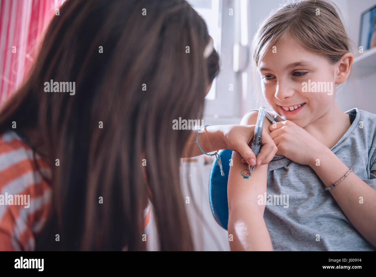 Ragazza iscritto tatuaggio sul braccio della sua fidanzata con penna Foto Stock