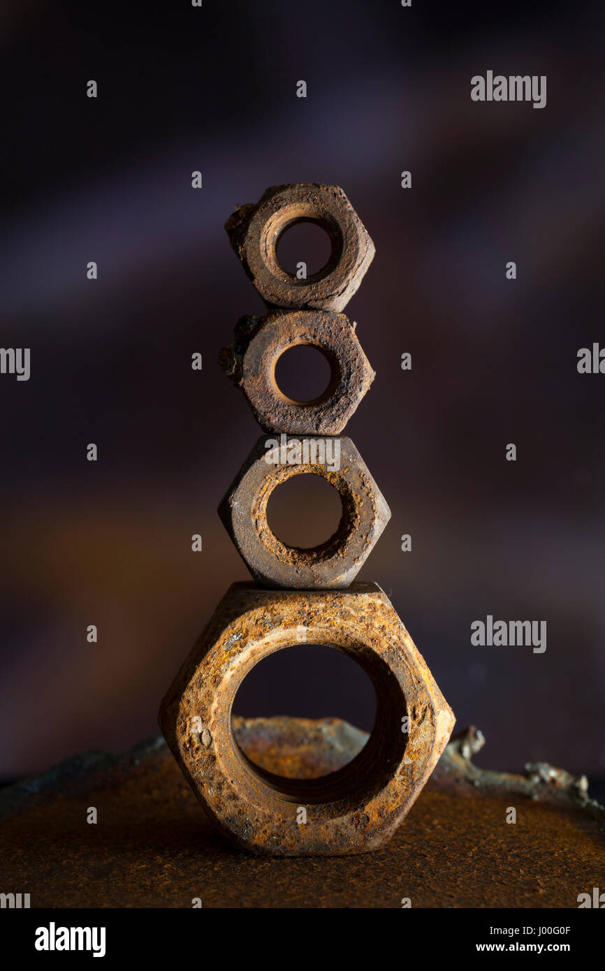 Composizione di macro di rusty vecchi dadi equilibrati sulla sommità della vicenda Foto Stock