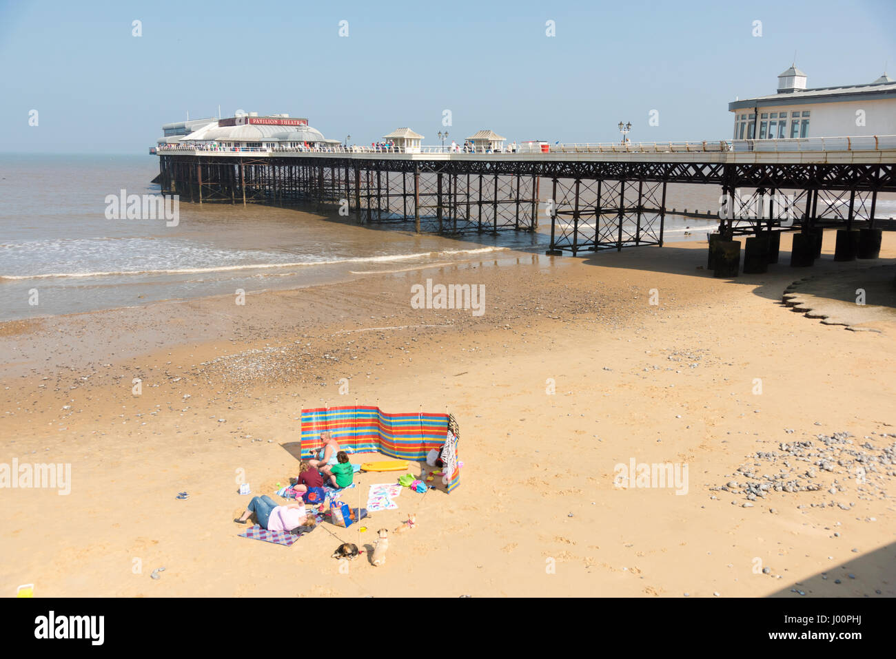 Cromer NORFOLK REGNO UNITO DAL 8 APRILE 2017. Persone sedersi sulla spiaggia dal famoso molo e godetevi il sole splendente nella calda primavera meteo. La temperatura è aumentata a 19 gradi centigradi ma c'era un freddo vento. Il bel tempo dovrebbe continuare nel corso del fine settimana. Credito Eales Julian/Alamy Live News Foto Stock