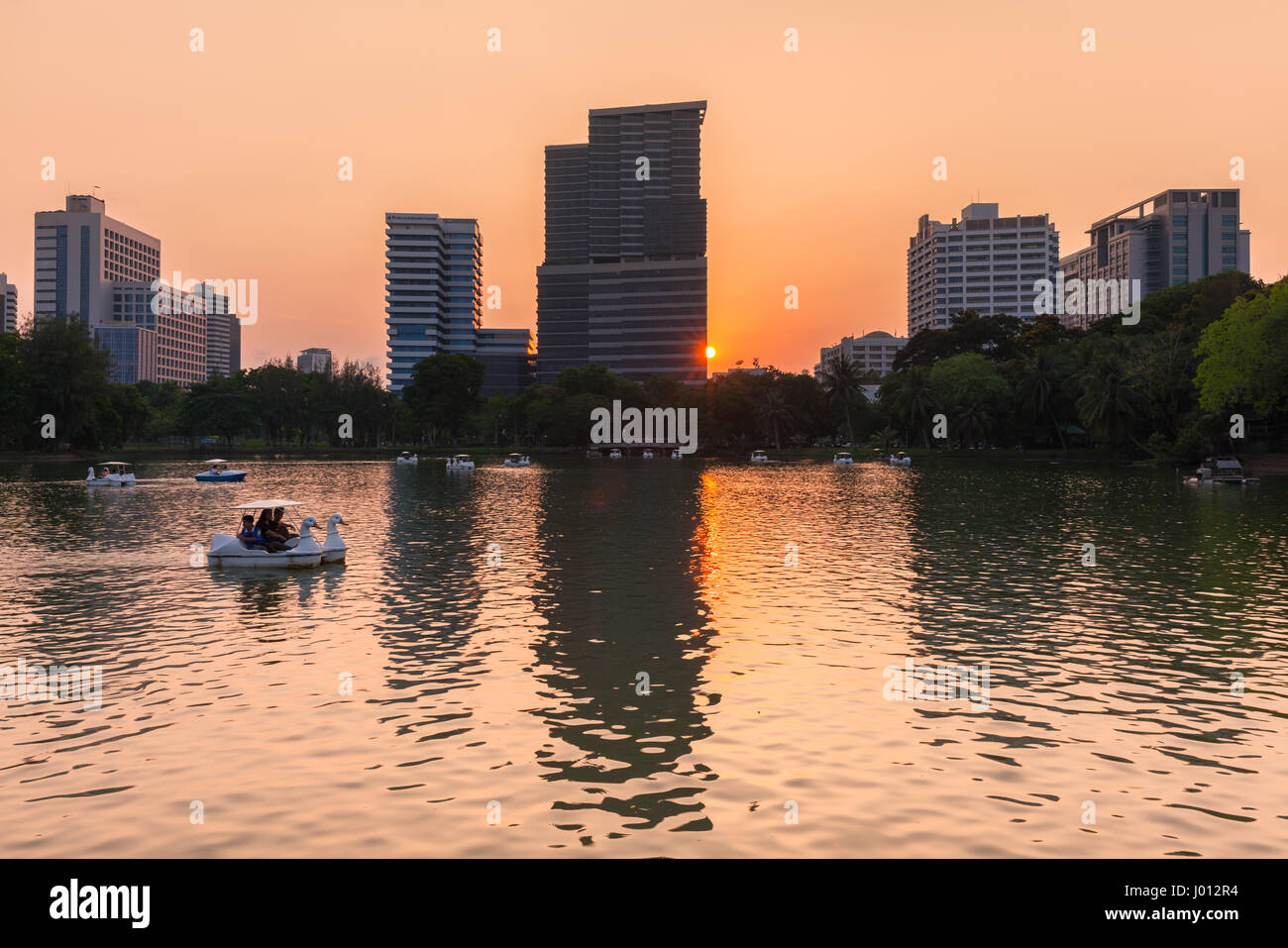 Vista al tramonto del lago e della città in pubblico Lumpini Park, Bangkok, Thailandia Foto Stock