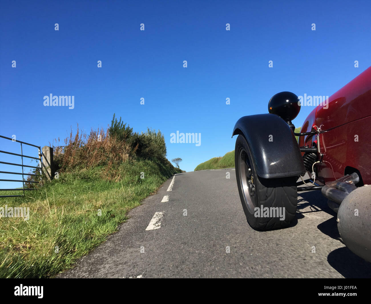 Auto sportiva rossa sulla guida a sinistra country road in Galles, Regno Unito Foto Stock