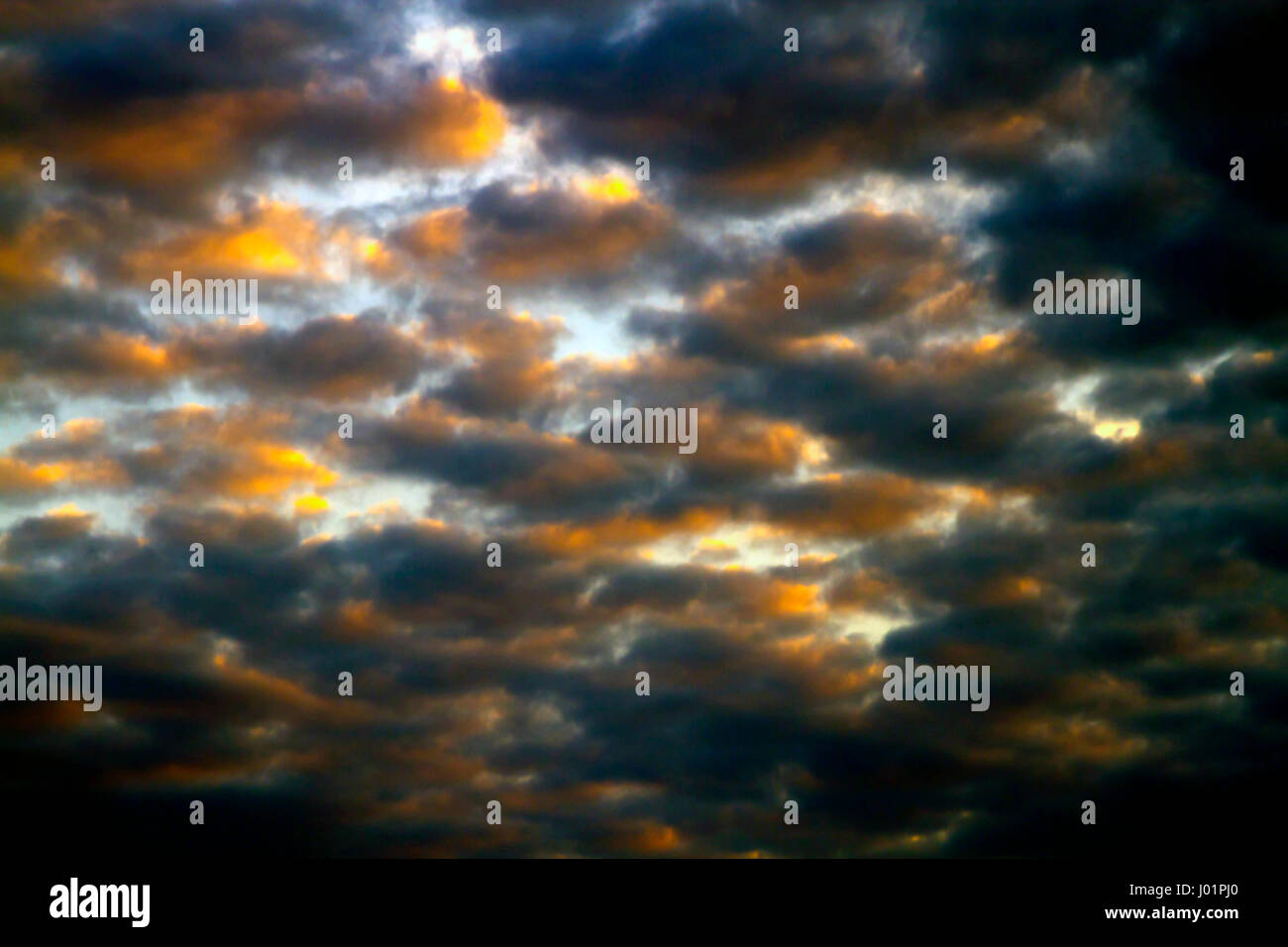 In contrasto, impressionistica cercando cluster le nuvole nel cielo blu sopra al tramonto Foto Stock