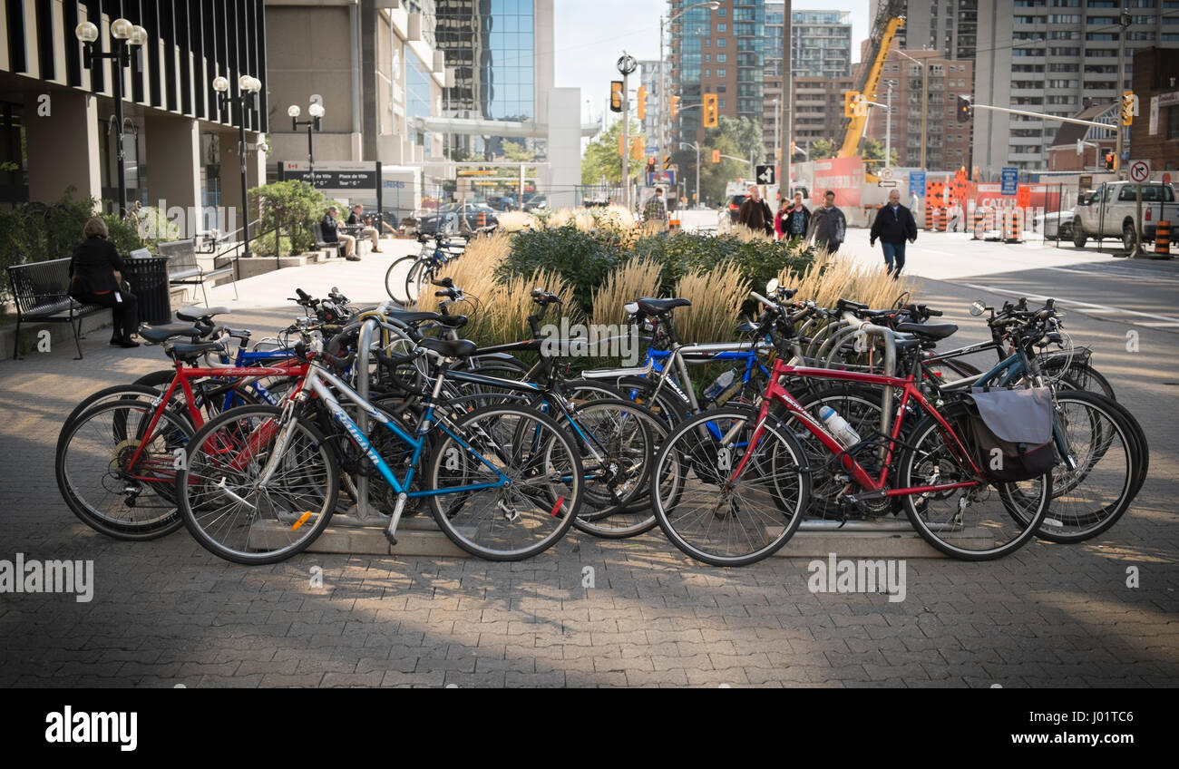 Un gruppo di commutor biciclette parcheggiate su un ampio marciapiede nel centro cittadino di Ottawa, Canada Foto Stock