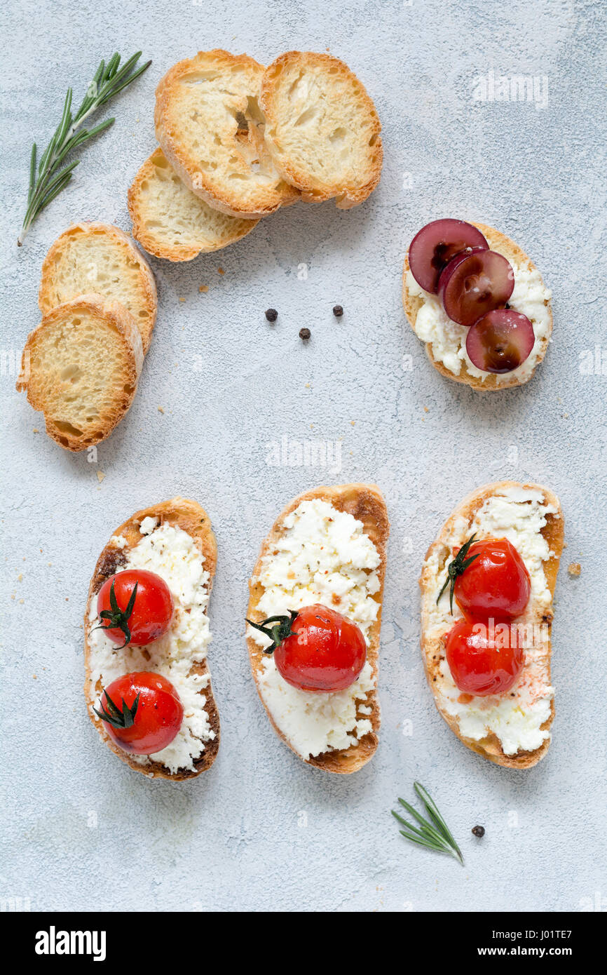 La bruschetta, italiano un aperitivo o uno snack con arrosti di pomodori ciliegia e diffusione fresco formaggio. Vista superiore Foto Stock