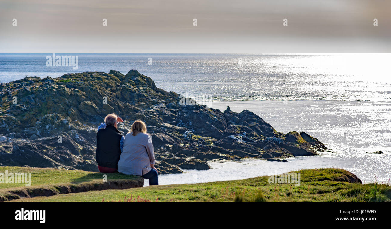 Coppia di mezza età che guarda al mare al suono, Isola di Man. Foto Stock
