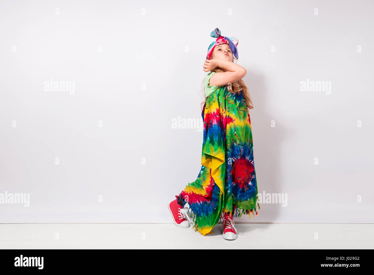 Felice bambino biondo ragazza in hippie abiti colorati contro il muro bianco Foto Stock