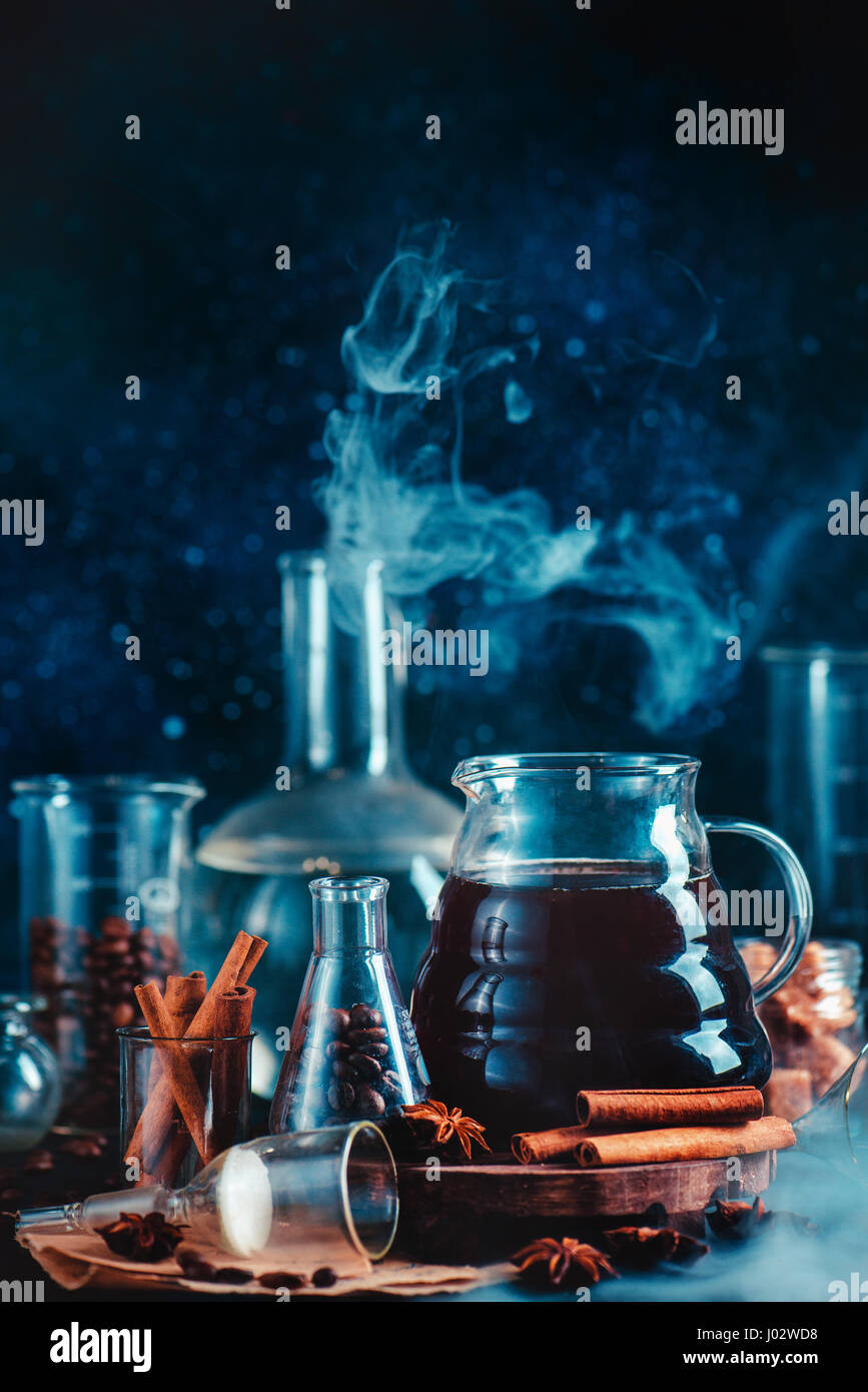 Ancora scientifica la vita con caffettiera, tazze, spezie, anice e cannella e vetreria di laboratorio su sfondo scuro Foto Stock