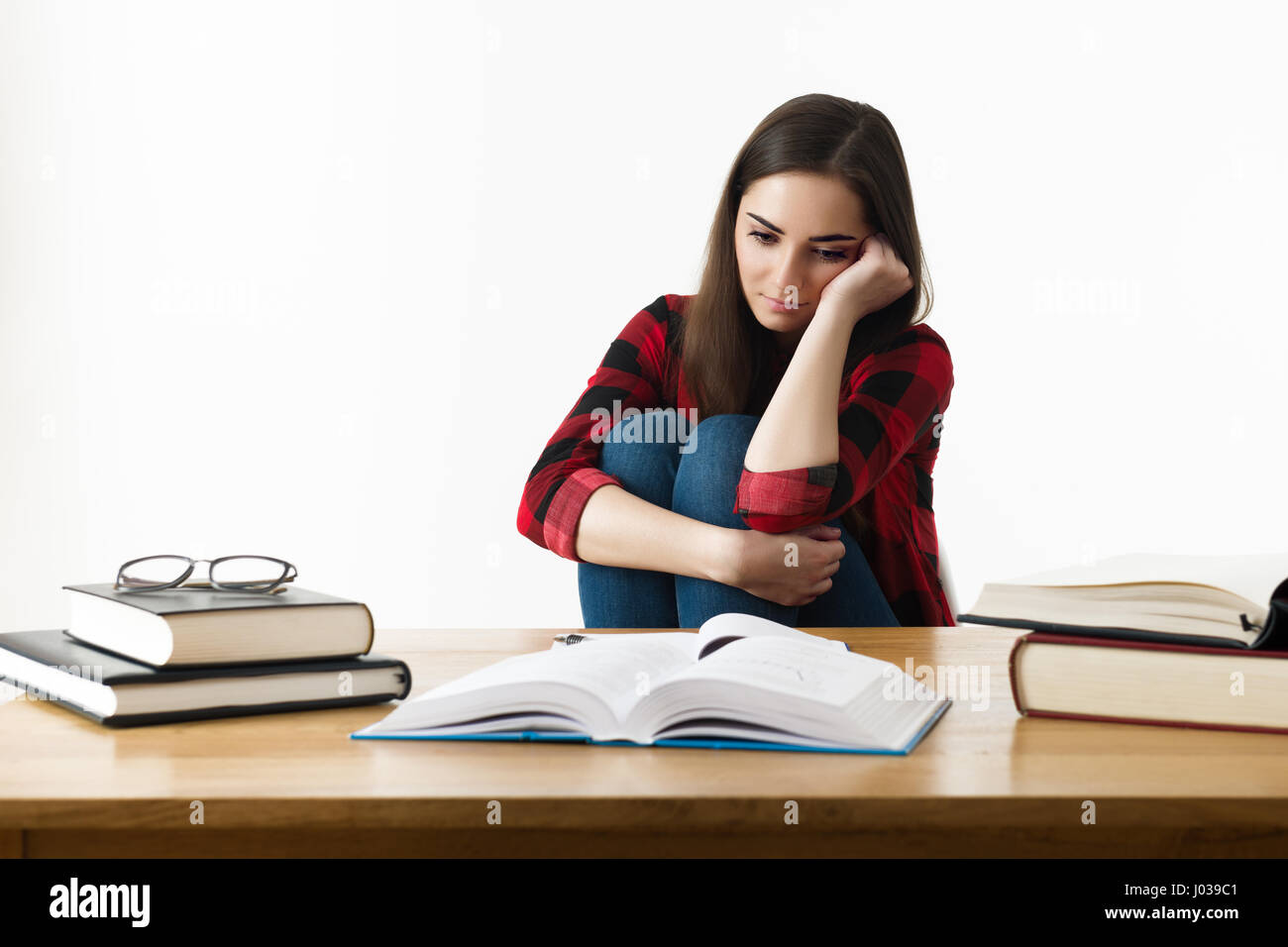 Frustrata studentessa. giovane studente con espressione disperata seduto alla sua scrivania. Foto Stock