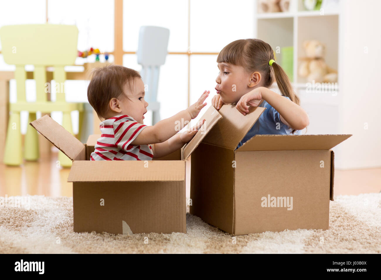 Bambino sorella e fratello toddler giocando in scatole di cartone Foto Stock