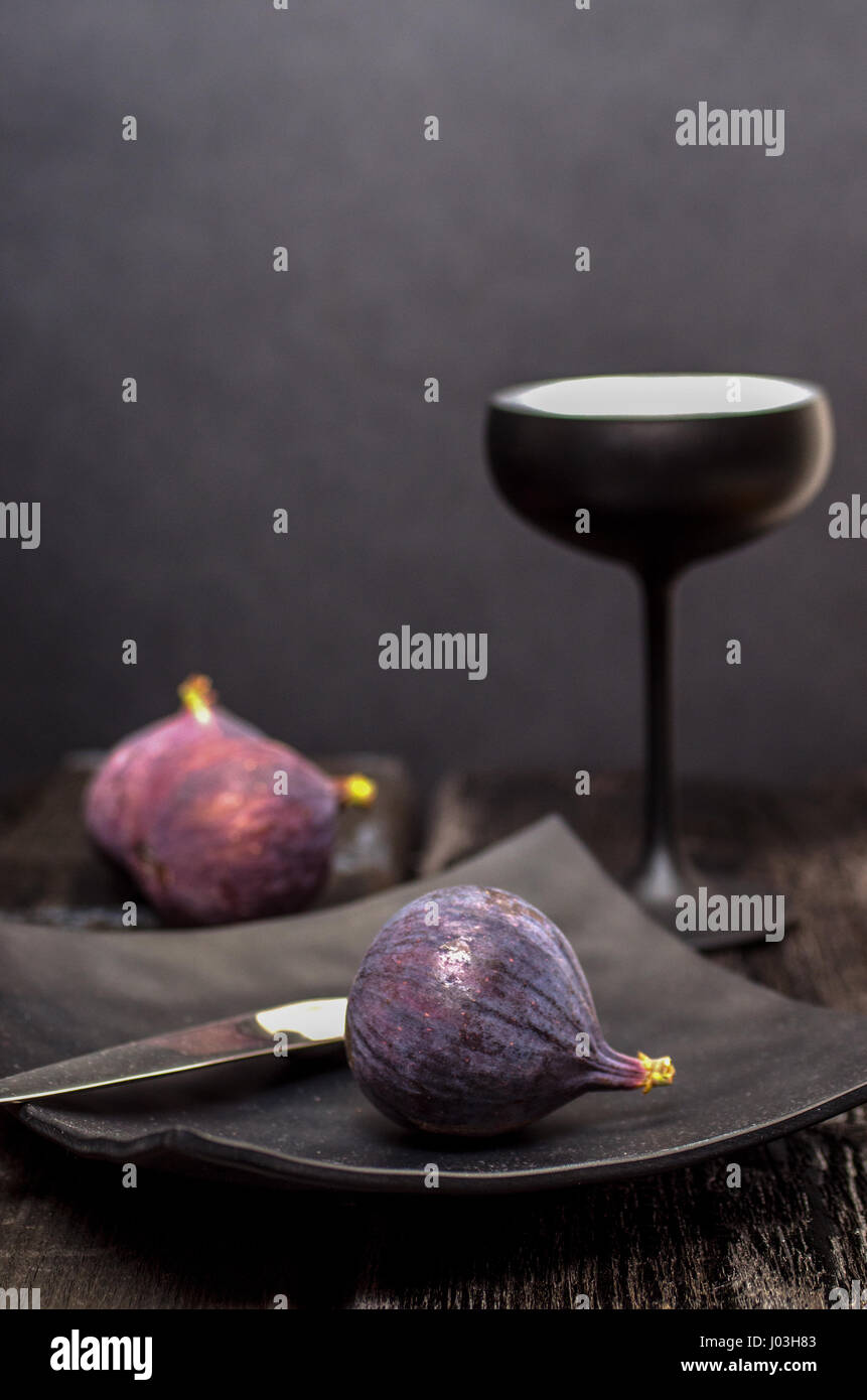 Figg, insolito cucchiaio, quadrato piatto nero e il bicchiere da cocktail su sfondo nero Foto Stock
