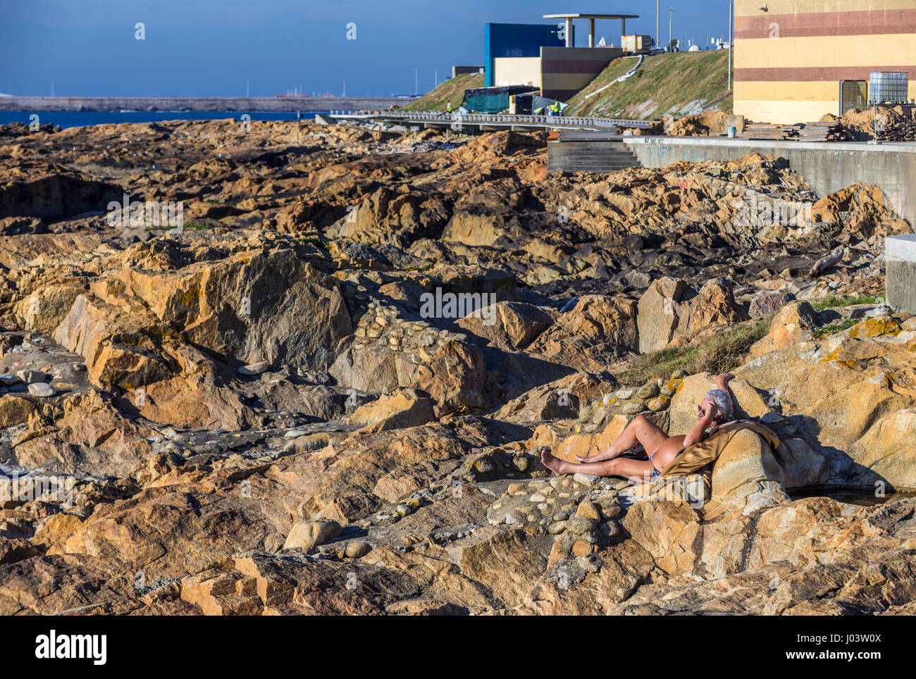 L uomo a prendere il sole su una roccia di Oceano Atlantico shore Nevogilde parrocchia civile della città di Porto, la seconda più grande città in Portogallo Foto Stock