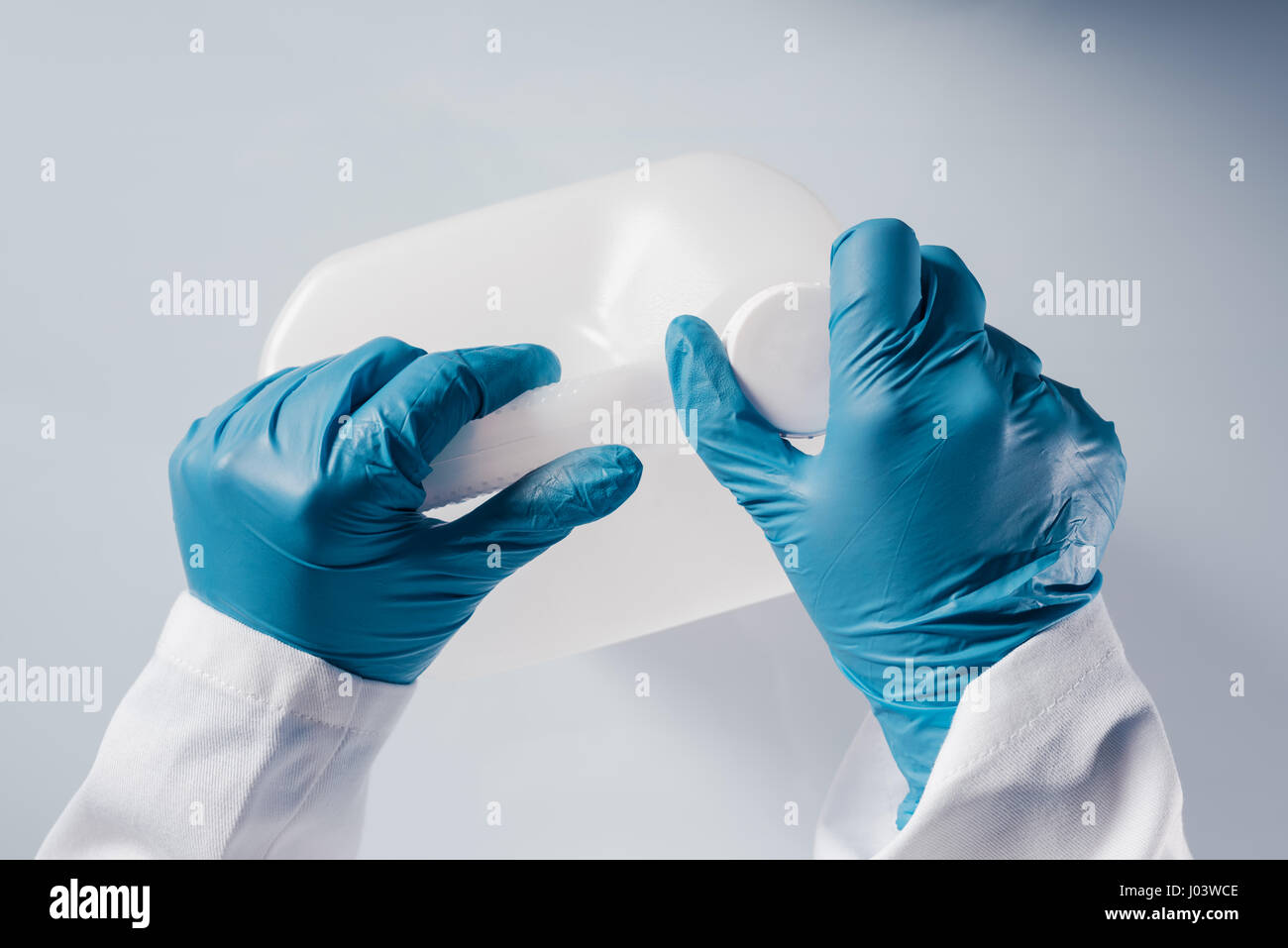 Scienziato chimico di apertura non marcato bianco del serbatoio di plastica canister con sostanze chimiche sulla tabella di laboratorio Foto Stock