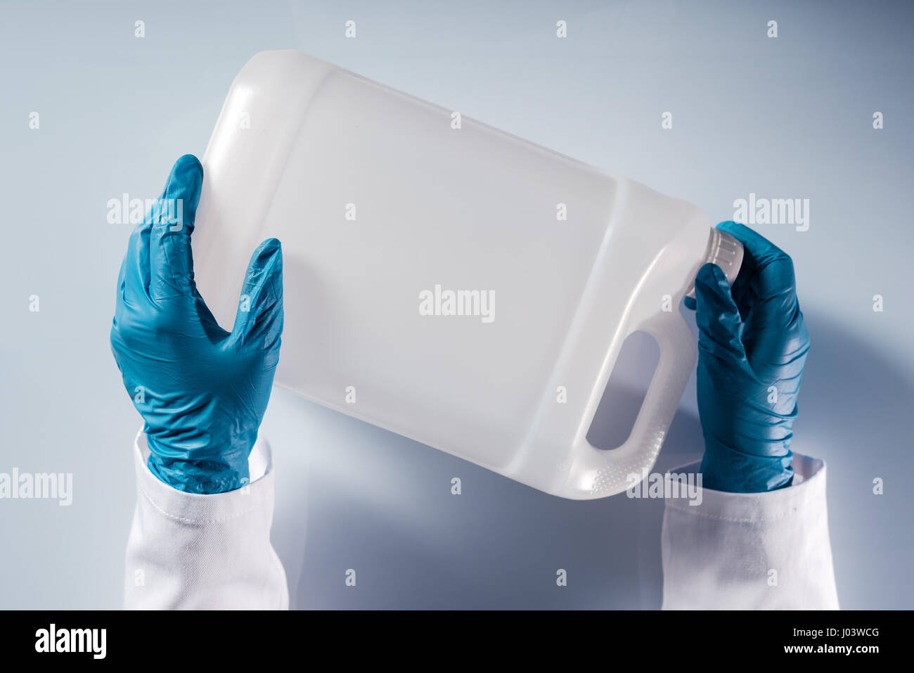 Scienziato chimico di apertura non marcato bianco del serbatoio di plastica canister con sostanze chimiche sulla tabella di laboratorio Foto Stock