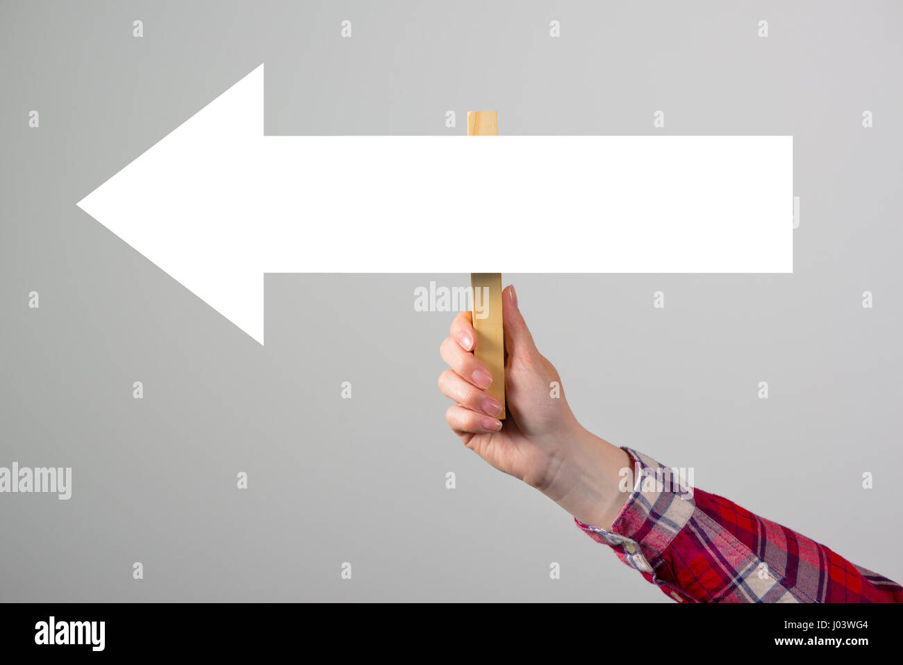 Donna che mantiene la direzione di guida segno di freccia in mano, concetto di orientamento e il processo decisionale Foto Stock