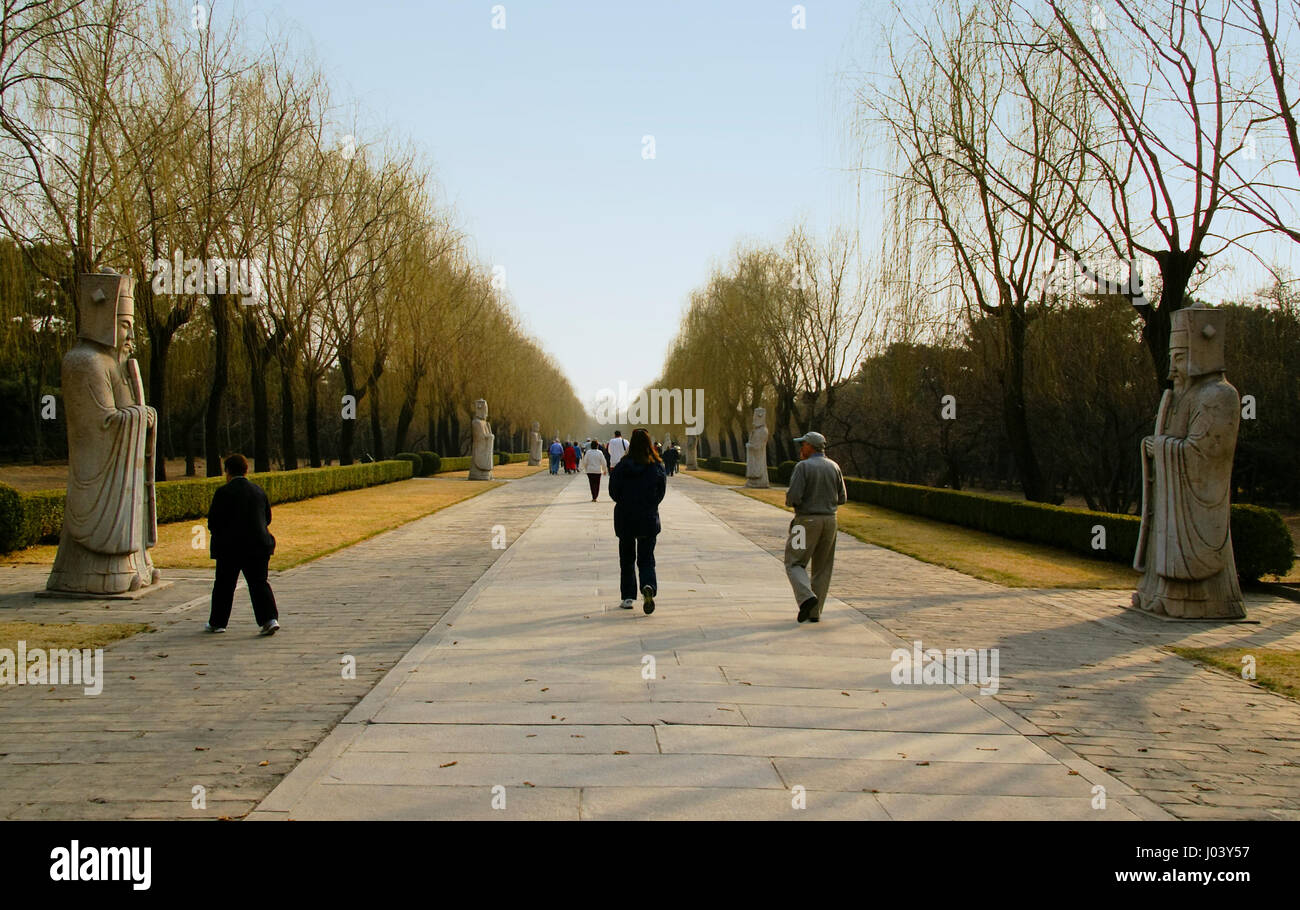 I visitatori a piedi lungo la Via Sacra vicino le Tombe dei Ming. Pechino, Cina. Nel tardo pomeriggio su un inizio di giornata di primavera con gli alberi appena iniziando a verde. Foto Stock