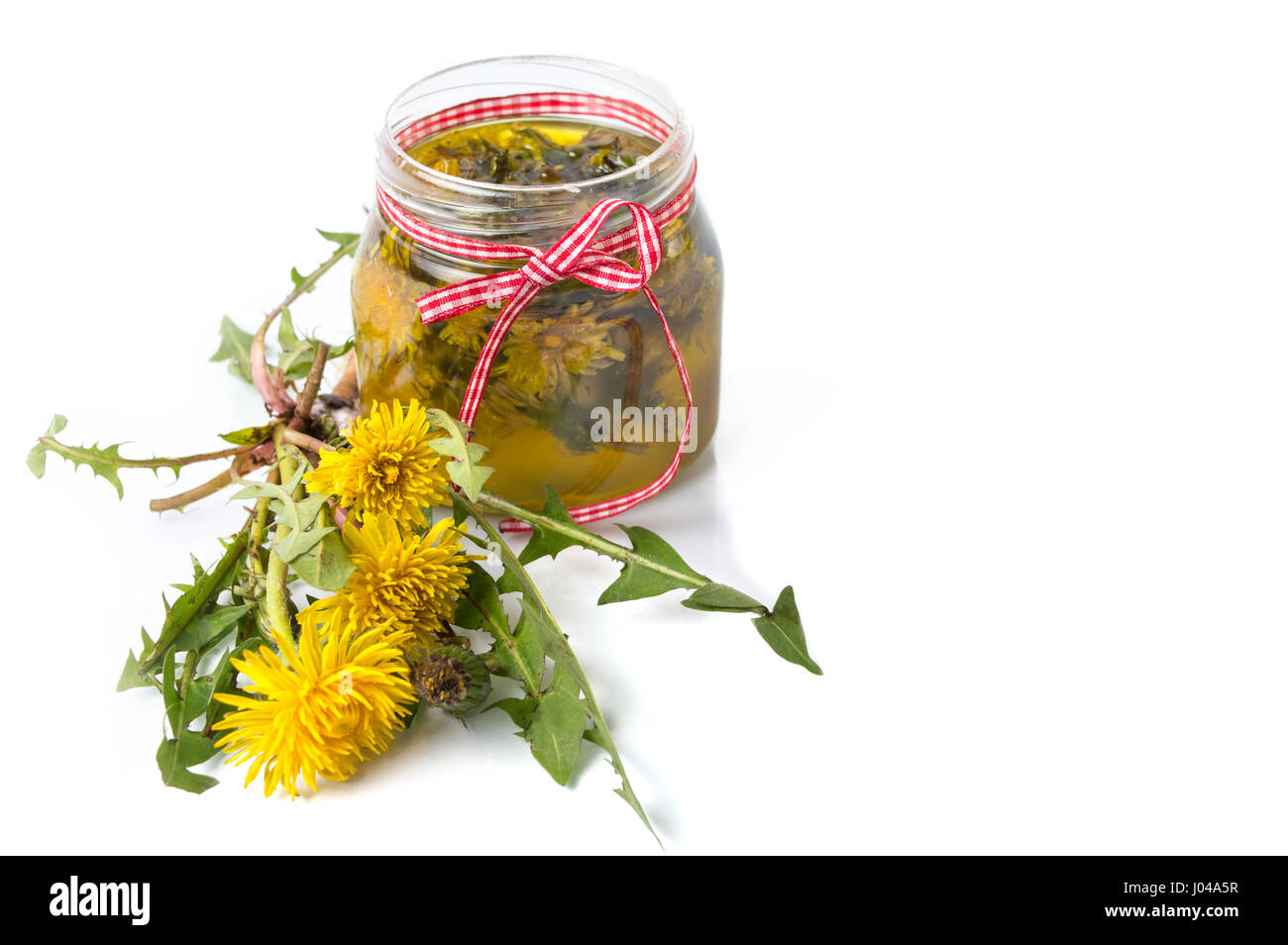 Fiori di tarassaco e l'olio in un recipiente isolato Foto Stock