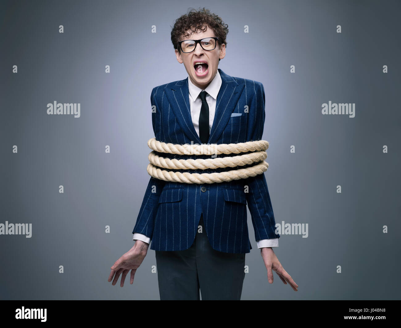 Funny business man legato con corda urlando per aiutare Foto Stock