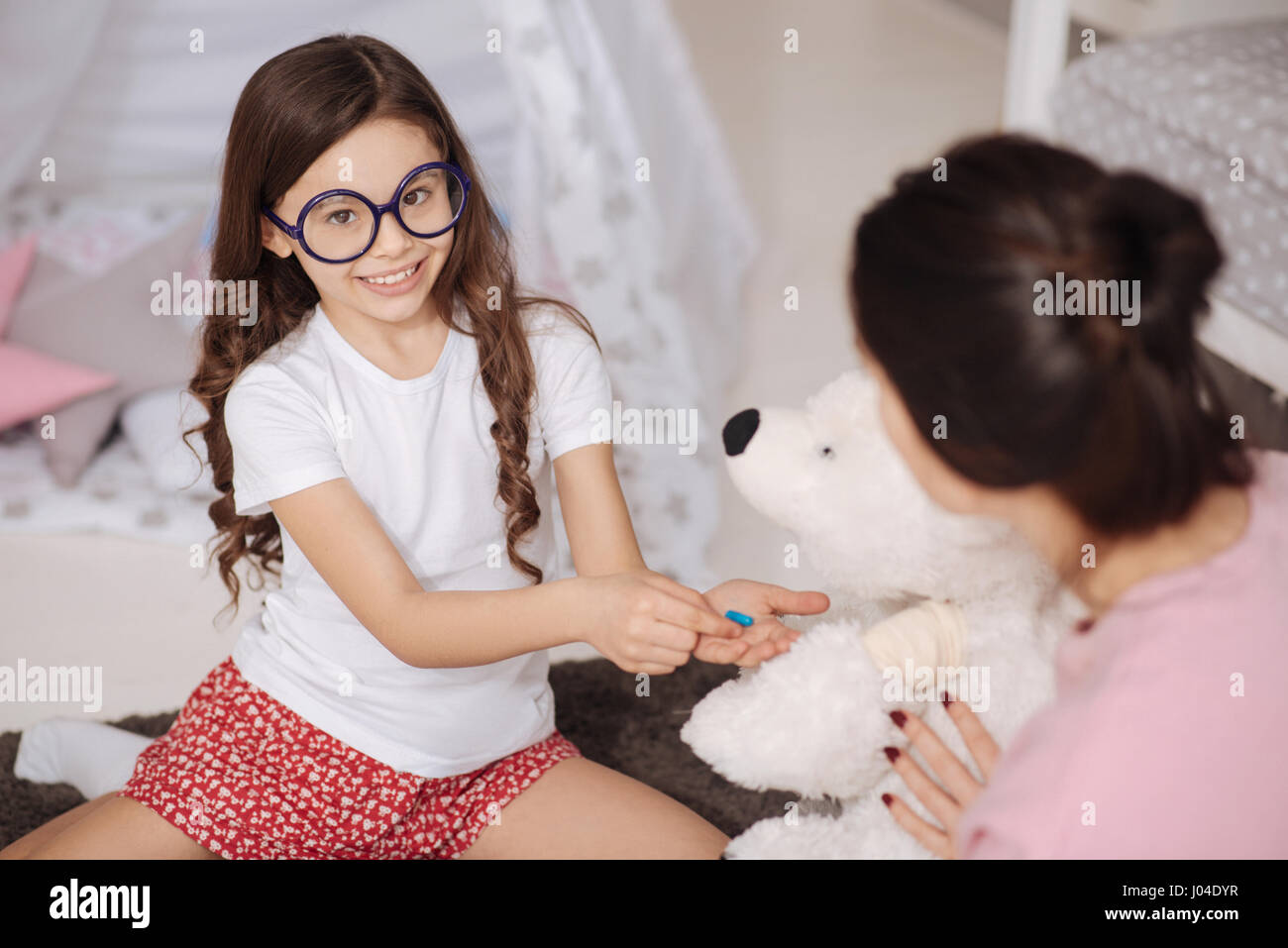 Affascinante piccolo ragazza avendo cura di giocattolo preferito a casa Foto Stock