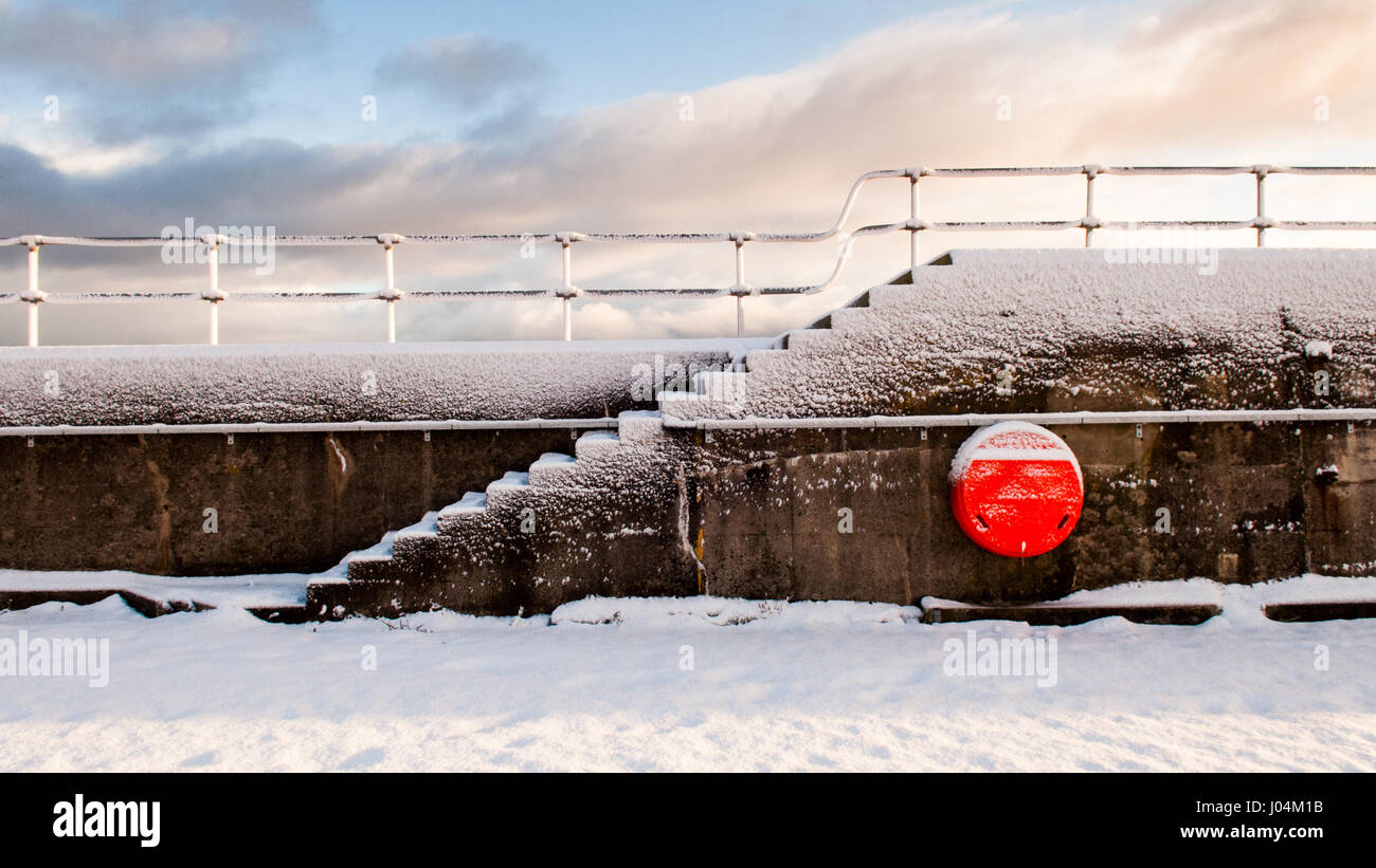 Vento-neve soffiata ricopre la parete del mare a helmsdale harbour nel lontano Nord delle Highlands della Scozia. Foto Stock