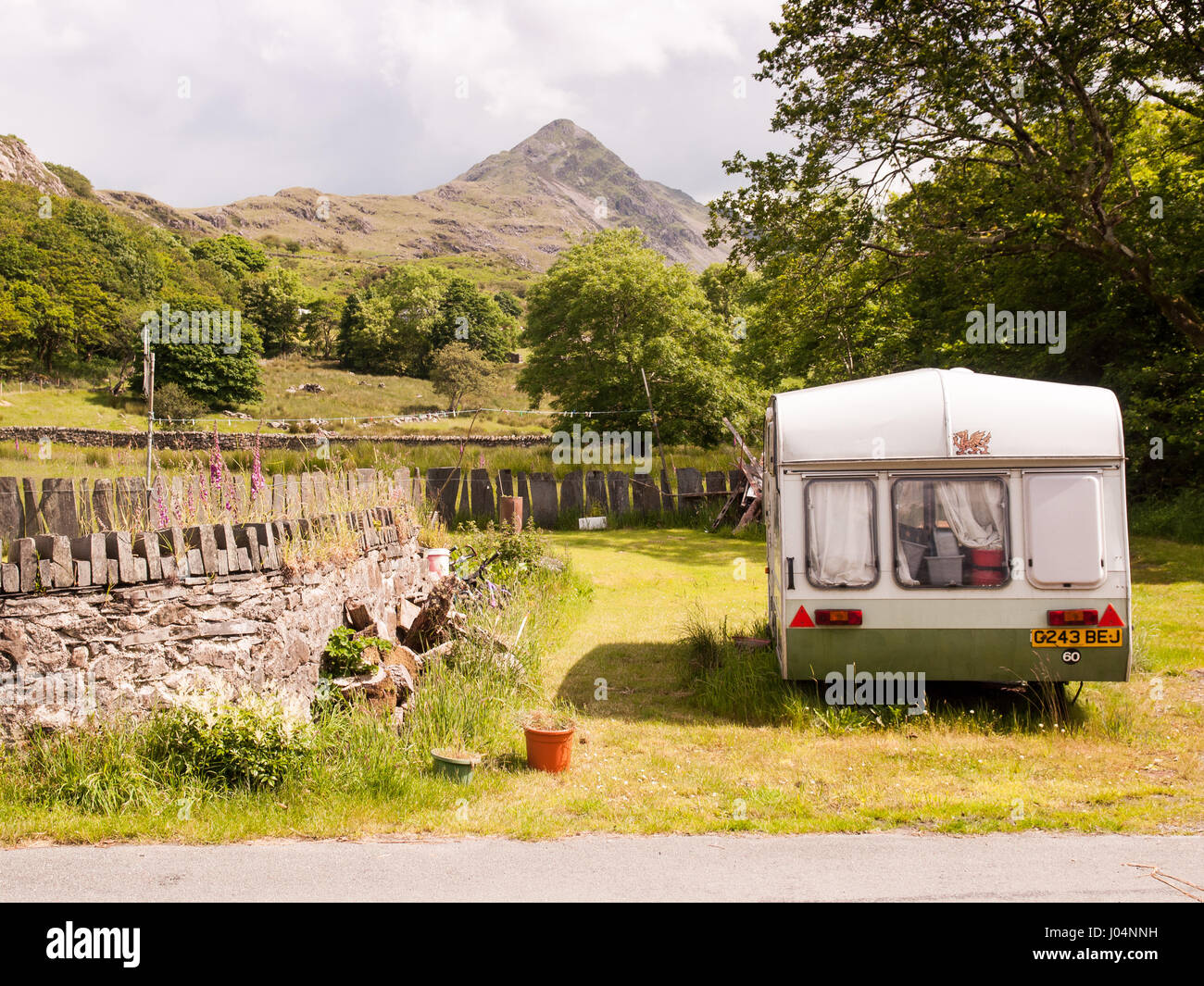 Montagna Cnicht sorge dietro un giardino e caravan accanto a una corsia in un piccolo villaggio nel Parco Nazionale di Snowdonia nel Galles del Nord. Foto Stock