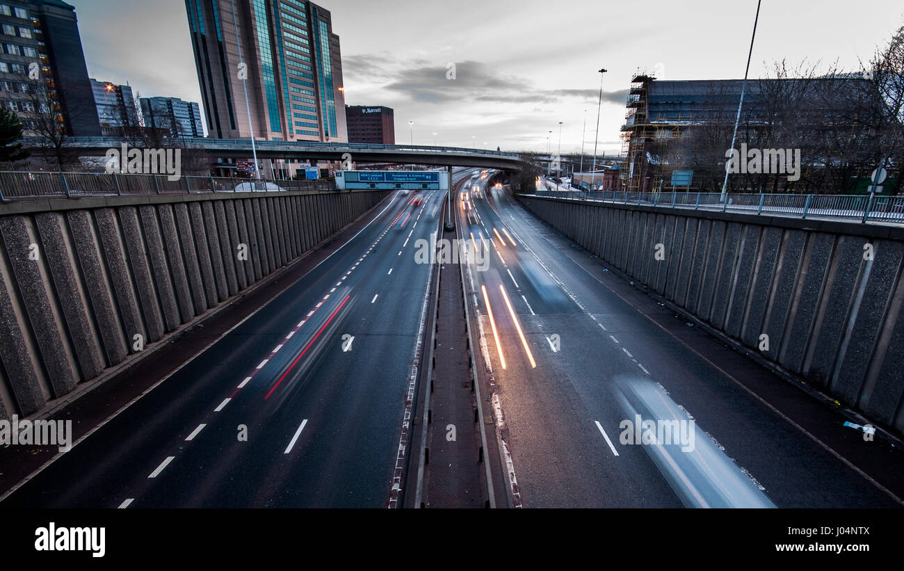 Glasgow, Scotland, Regno Unito - 9 gennaio 2011: il traffico passa lungo l autostrada m8 road passato edifici per uffici e blocchi a torre nella zona centrale di Glasgow al tramonto Foto Stock