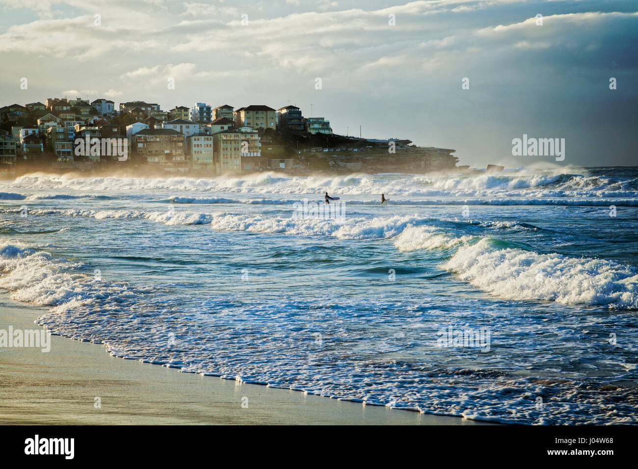 La spiaggia di Bondi, Sydney, Australia, in una bella mattina winterr con buoni surf, due surfisti solo a piedi fuori nelle onde. Foto Stock