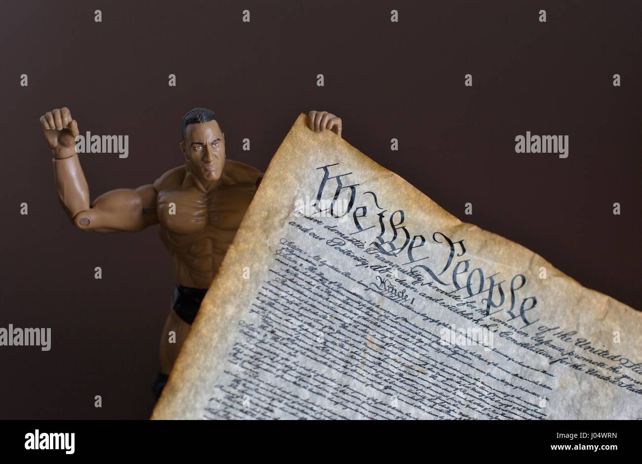 Un maschio di azione figura uomo forte bambola in possesso di una copia della costituzione degli Stati Uniti. Foto Stock