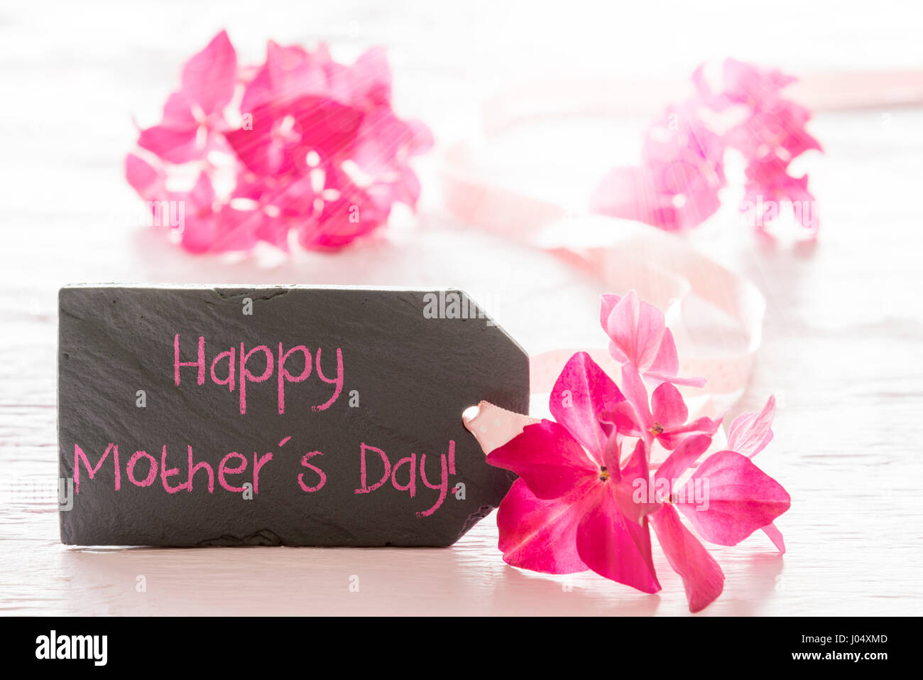 Lastra di ardesia con testo in inglese felice festa della mamma. Fiore di primavera sbocciano i fiori di ortensie. Bianco lucido Sfondo di legno Foto Stock