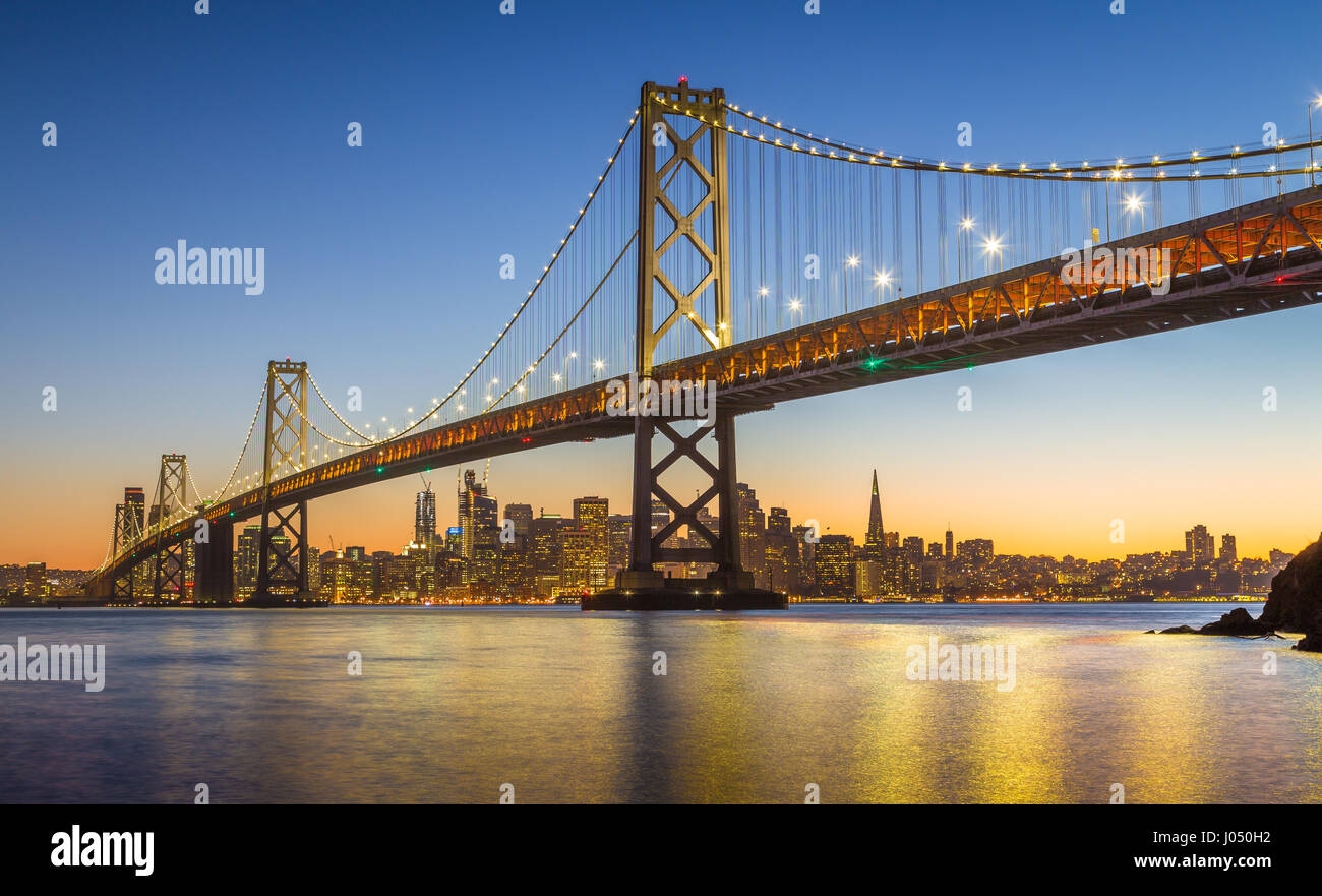 Classic vista panoramica del famoso Oakland Bay Bridge con lo skyline di San Francisco illuminata nella bellissima twilight dopo il tramonto, CALIFORNIA, STATI UNITI D'AMERICA Foto Stock