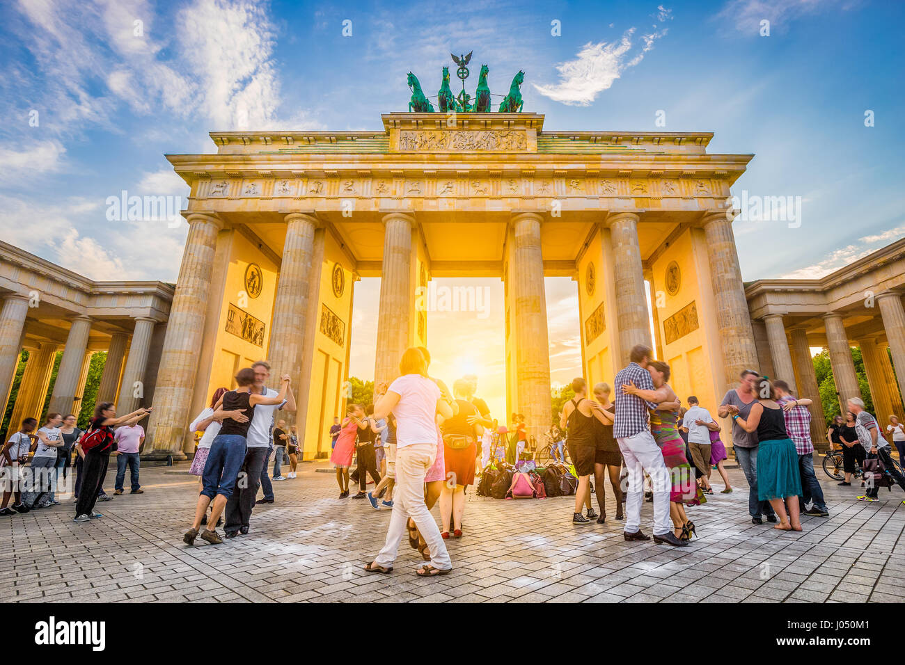 La gente ballare nella parte anteriore della famosa Porta di Brandeburgo, un simbolo di pace e di unità e punto di riferimento storico, in golden luce della sera al tramonto, Berlino Foto Stock