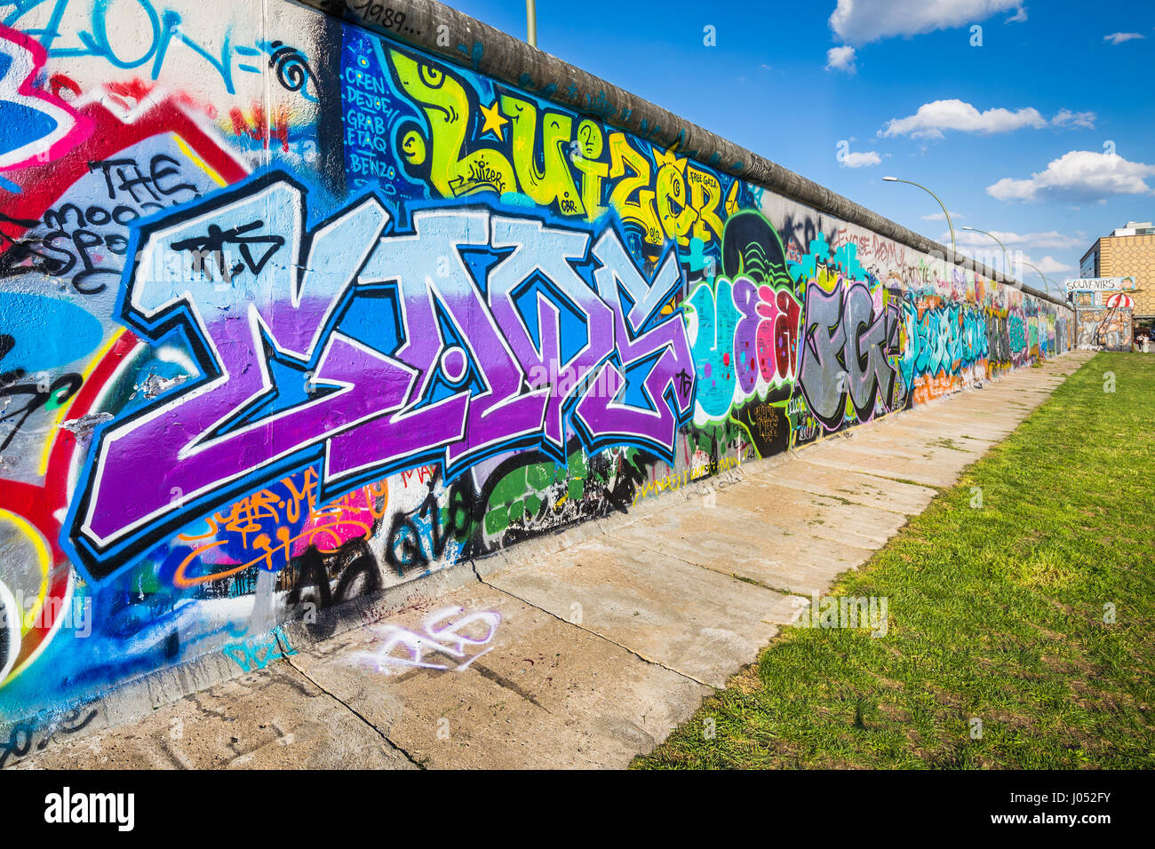Vista panoramica del famoso muro di Berlino decorate con colorati graffiti street art alla storica East Side Gallery in una giornata di sole con cielo blu e nuvole Foto Stock
