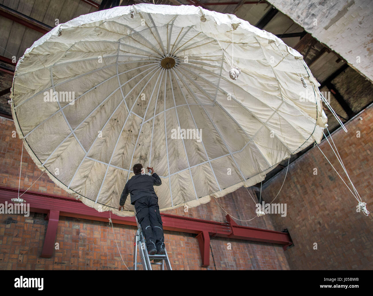 Peenemuende, Germania. 29 Mar, 2017. Museo dipendente Uwe Boettger mette su una statunitense paracadute pilota in una mostra presso il Museo Historical-Technical ("Historisch-Technisches Museum') in Peenemuende, Germania, 29 marzo 2017. Una mostra sul trattamento del western-allied e Eastern-European prigionieri di guerra nei campi tedeschi durante la Seconda Guerra Mondiale si apre al Museo Historical-Technical Peenemuende (HTM) il 30 marzo 2017. Foto: Jens Büttner/dpa-Zentralbild/dpa/Alamy Live News Foto Stock