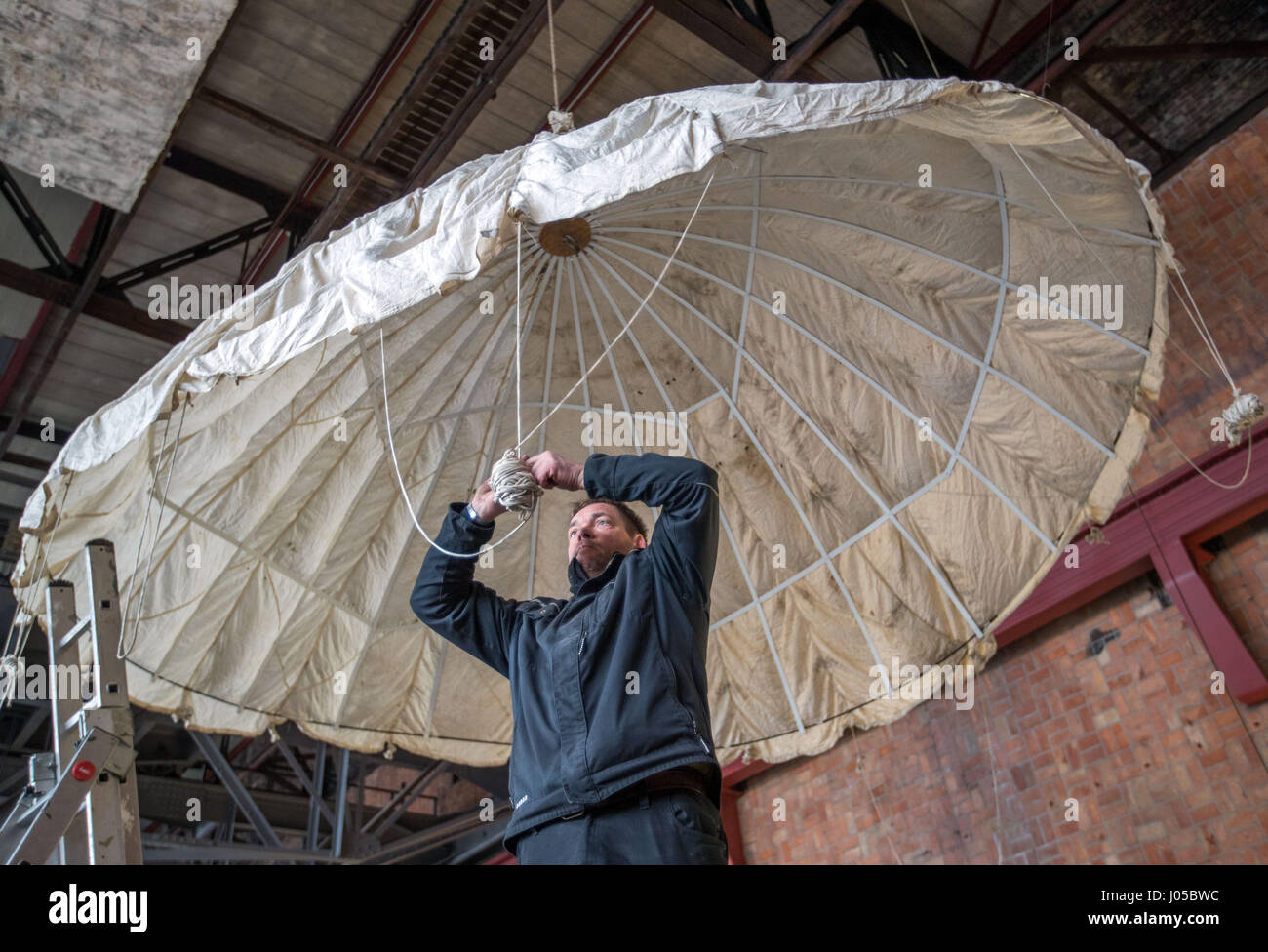 Peenemuende, Germania. 29 Mar, 2017. Museo dipendente Uwe Boettger mette su una statunitense paracadute pilota in una mostra presso il Museo Historical-Technical ("Historisch-Technisches Museum') in Peenemuende, Germania, 29 marzo 2017. Una mostra sul trattamento del western-allied e Eastern-European prigionieri di guerra nei campi tedeschi durante la Seconda Guerra Mondiale si apre al Museo Historical-Technical Peenemuende (HTM) il 30 marzo 2017. Foto: Jens Büttner/dpa-Zentralbild/dpa/Alamy Live News Foto Stock