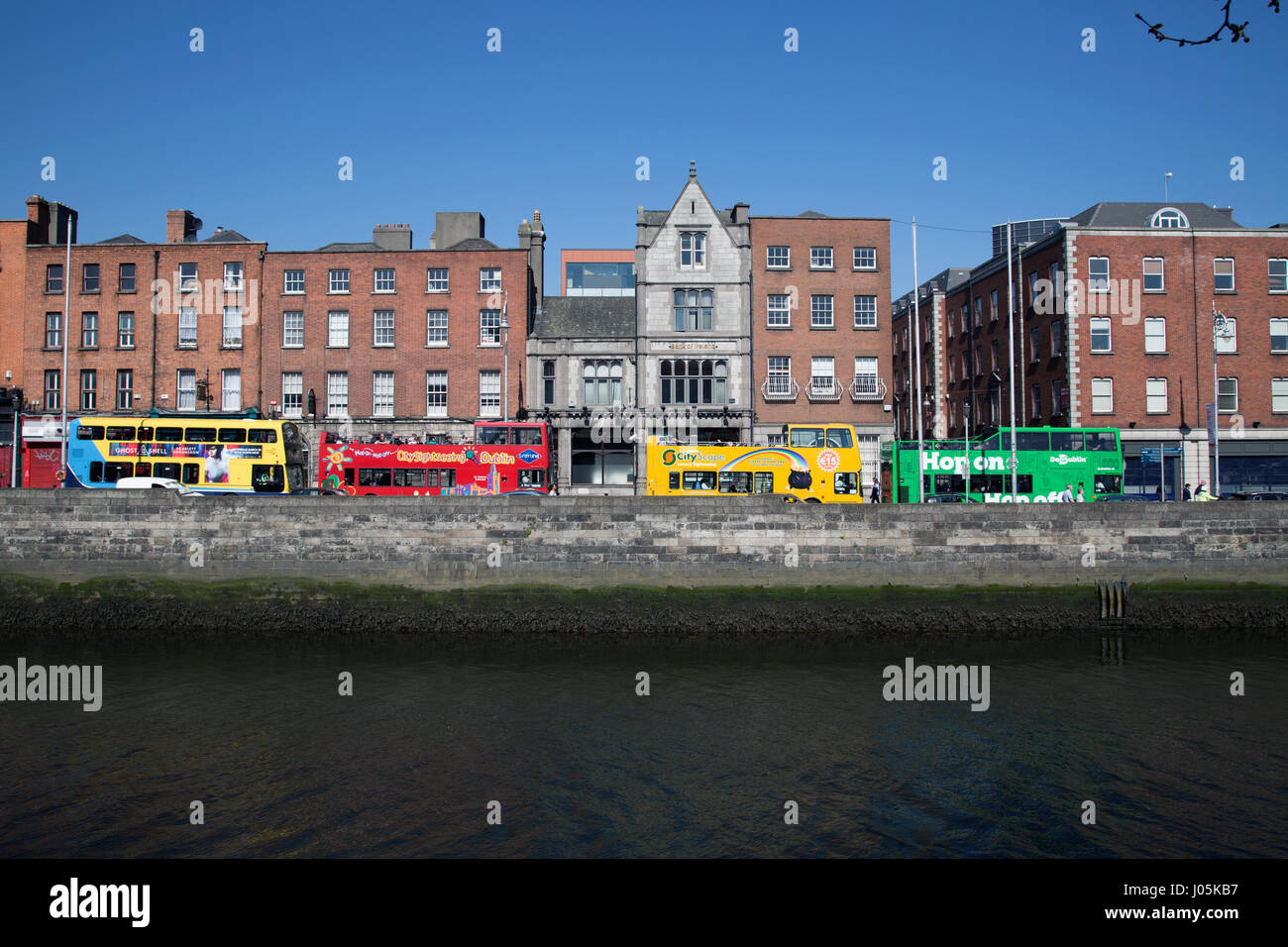 Gli autobus turistici allineati lungo il fiume Liffey nella città di Dublino, Irlanda. Foto Stock