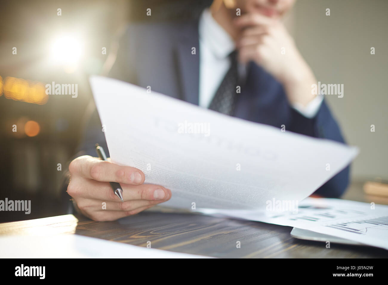 Closeup ritratto di un irriconoscibile imprenditore di successo vestita di nero vestito formale dei documenti di analisi e statistiche di finanza alla scrivania, pensando Foto Stock