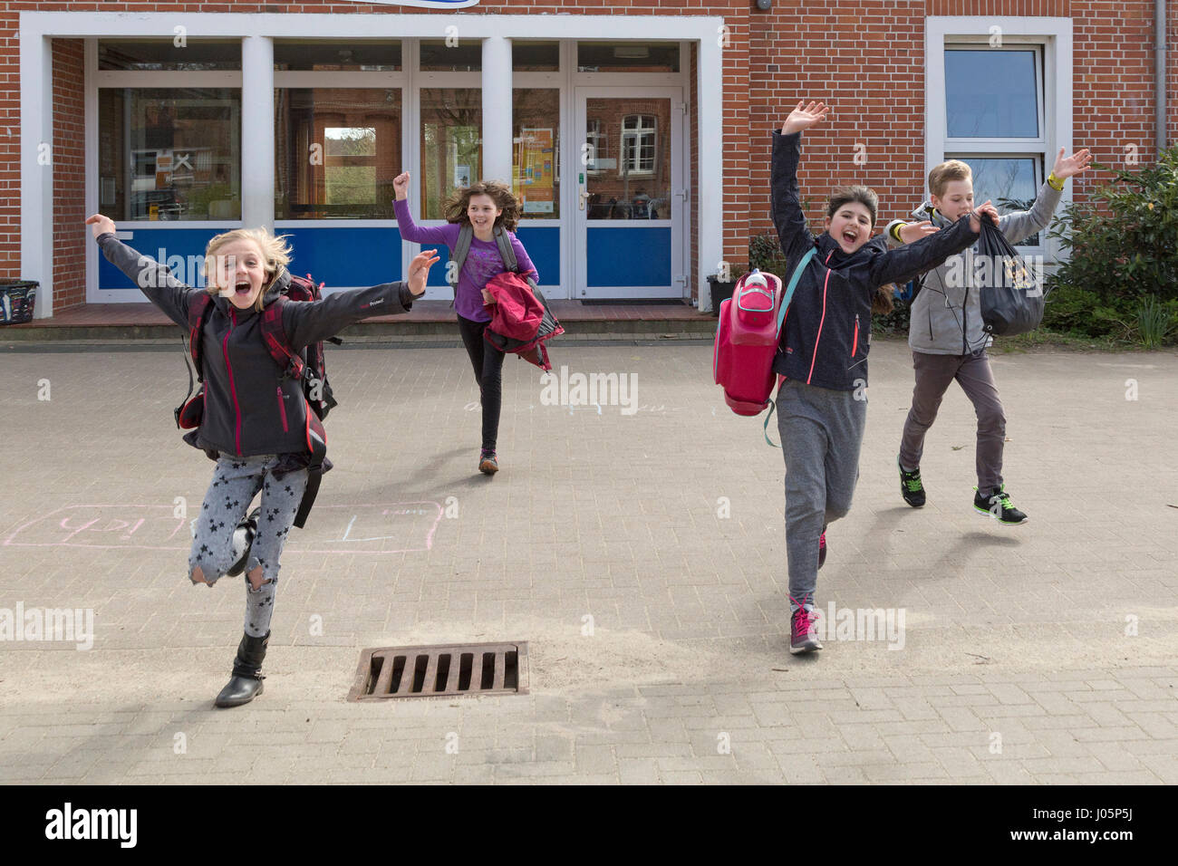 Alunni di scuola primaria in esecuzione nel loro vacanze felicemente, Bassa Sassonia, Germania Foto Stock